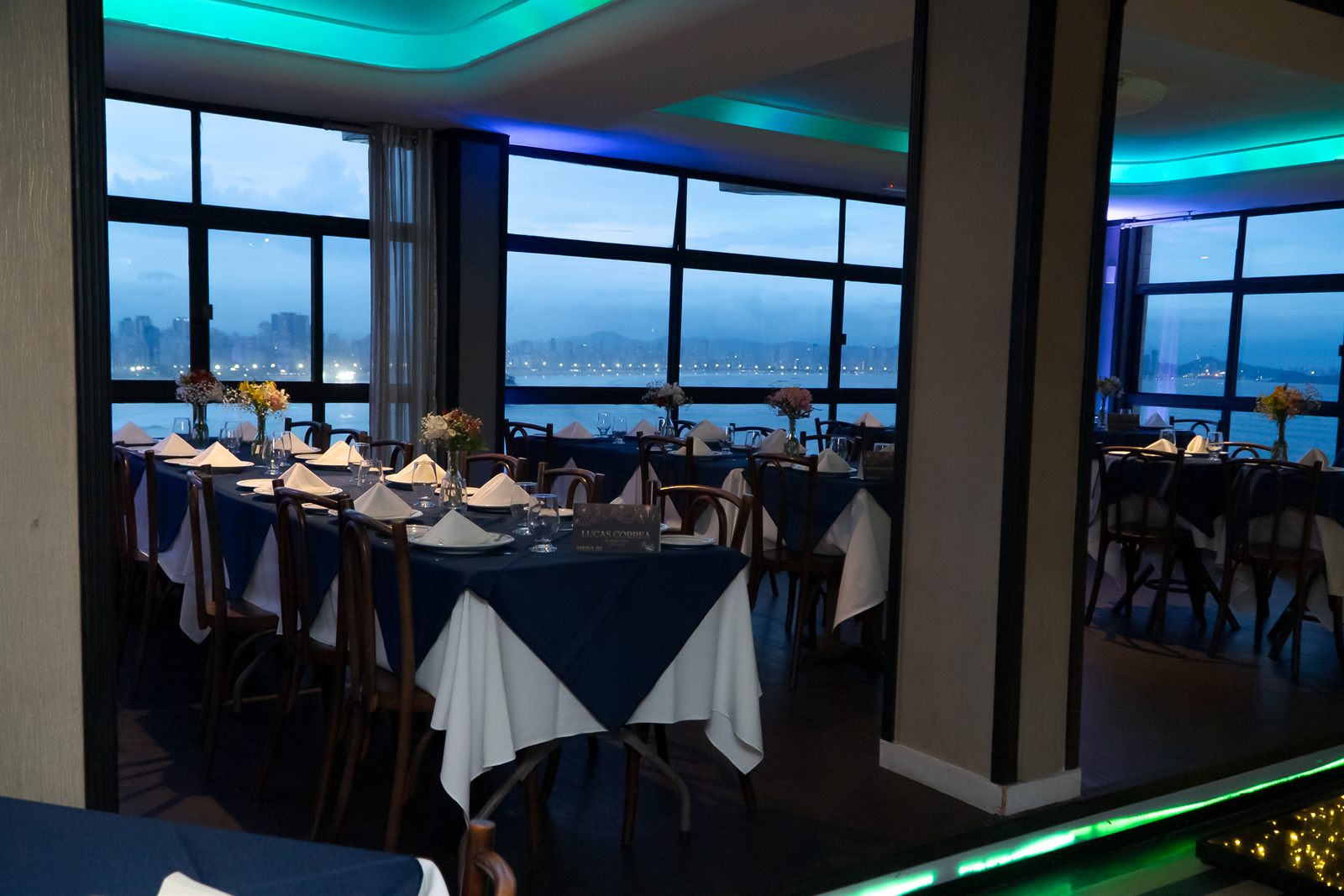 Salão, pista iluminada e vista para a orla ao entardecer